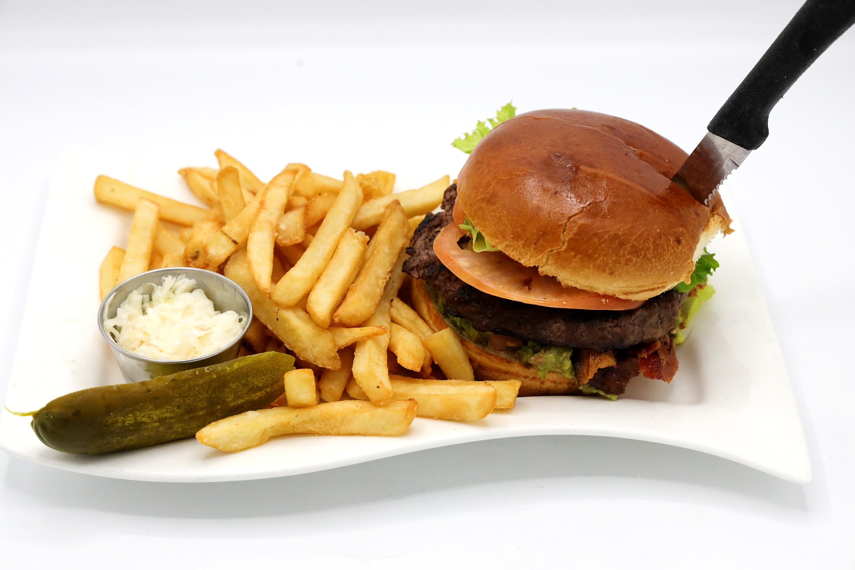 Specialty burger on a brioche bun with fries, coleslaw, and a pickle